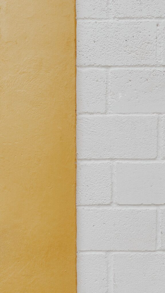 Frisch gestrichene Wand in Ocker neben weißem Mauerwerk